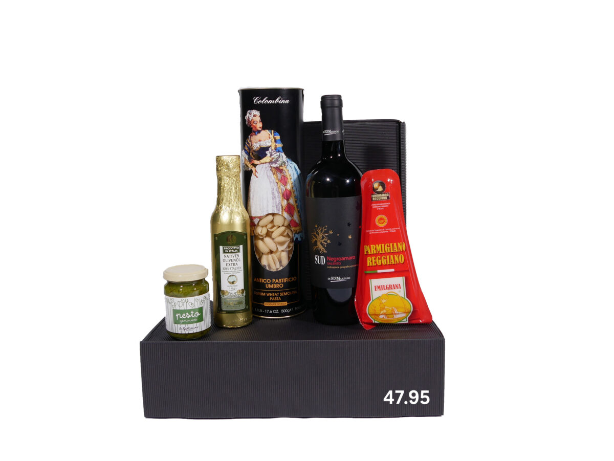 Ein Geschenkset bestehend aus einer Flasche Rotwein, einer Packung Parmigiano Reggiano Käse, einer goldenen Flasche Olivenöl, einer Dose Pesto und einer Packung Pasta in einer schwarzen Box mit der Preisangabe 47,95.