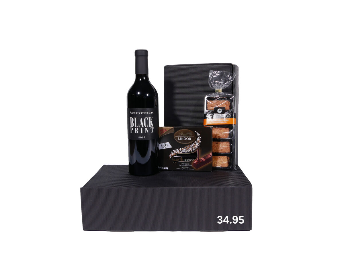 Schwarze Geschenkbox mit einer Flasche Schneider Black Print Wein, einer Packung Lindt Lindor Pralinen und einer Packung Gebäck auf weißem Hintergrund; Preisangabe 34,95.