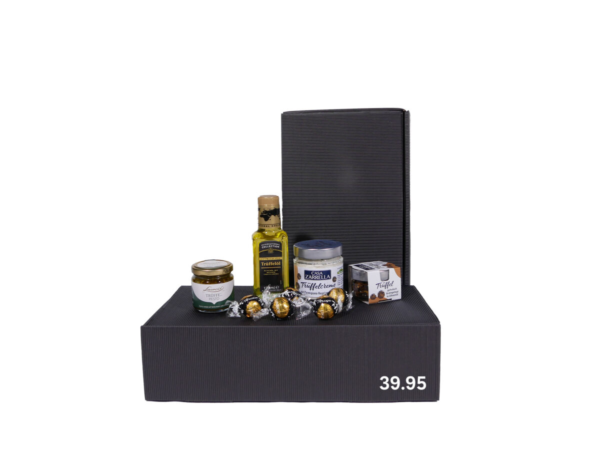 Geschenkset mit Trüffelprodukten, darunter Trüffelöl, Trüffelcreme, Trüffel in Gläsern und einige Pralinen, arrangiert auf einer schwarzen Box mit dem Preis 39,95 Euro darauf angegeben.