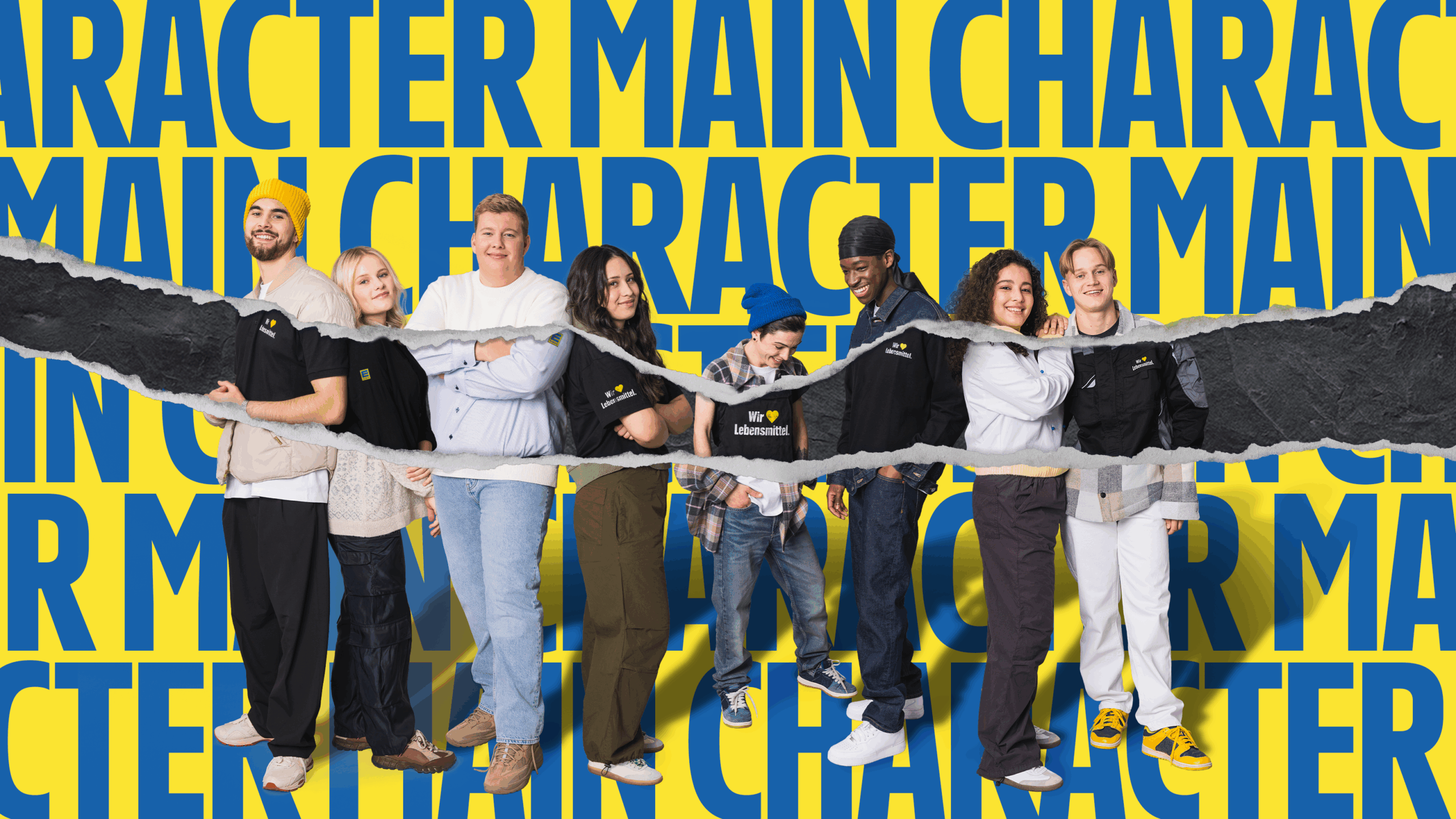 Eine Gruppe von Menschen in Freizeitkleidung steht vor einem gelben Hintergrund mit blauen Buchstaben, die "MAIN CHARACTER" formen. Einige tragen schwarze T-Shirts mit dem Logo "Wir lieben Lebensmittel". Ein zerrissenes Papierdesign zieht sich horizontal durch das Bild.